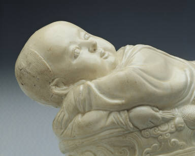 Pillow in the shape of a recumbent child with white glaze