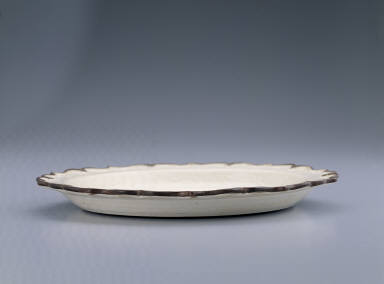 Lotus-rimmed dish with incised bamboo, rock, and floral design in white glaze