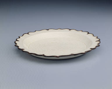 Lotus-rimmed dish with incised bamboo, rock, and floral design in white glaze