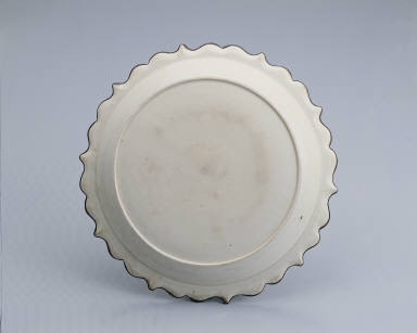 Lotus-rimmed dish with incised bamboo, rock, and floral design in white glaze