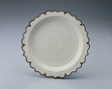 Lotus-rimmed dish with incised bamboo, rock, and floral design in white glaze