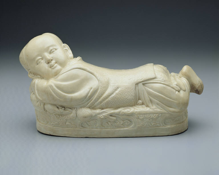Pillow in the shape of a recumbent child with white glaze